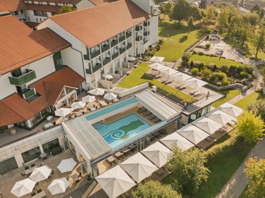 Luftaufnahme eines Hotels mit Außenpool, Sonnenterrasse, Garten und Liegebereichen.