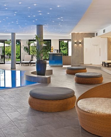 Heller Wellnessbereich mit Innenpool, Liegen und runden Sitzmöbeln in einem ruhigen Spa-Raum.